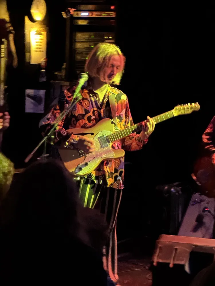 Jyonson Tsu singing with a guitar at Pour House