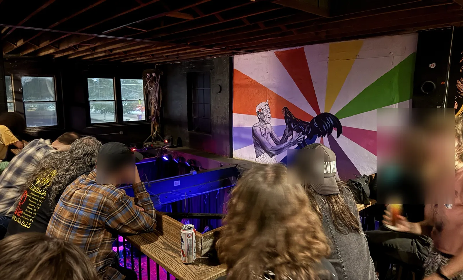 The balcony over the stage, by a mural of an old man holding a rooster against a burst of color