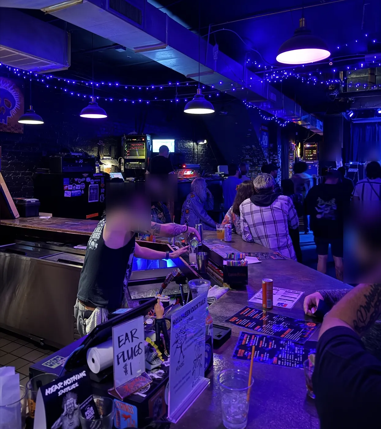 Inside under blue string lights: the bar, the sound desk, and the crowd near the stage