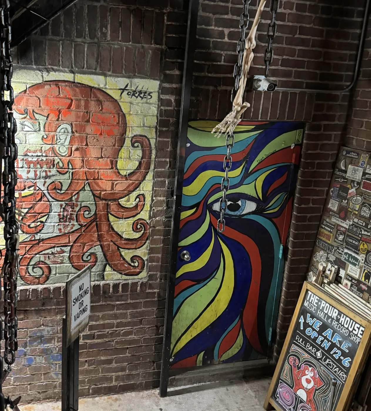 A painted octopus mural signed Torres beside a door painted in swirling stripes around one open eye