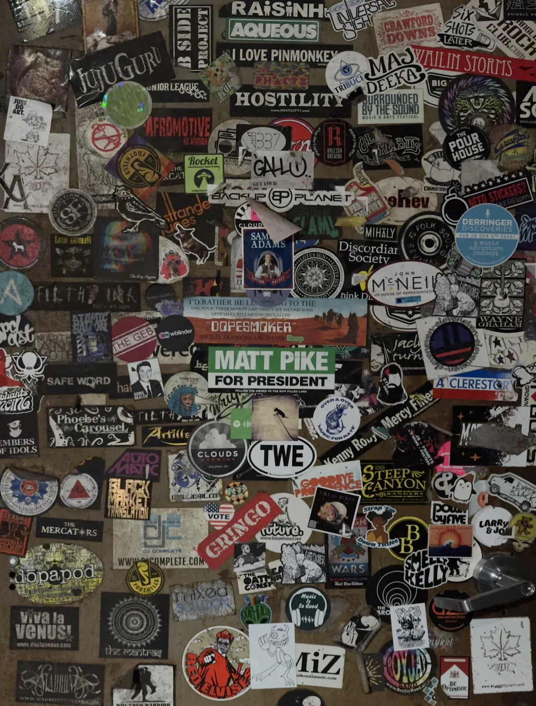 A steel door covered edge to edge in band and venue stickers